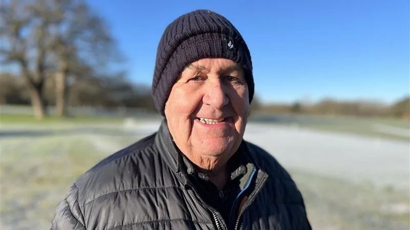 James Shelford wears a dark blue jacket and wooly hat as he smiles into the camera.