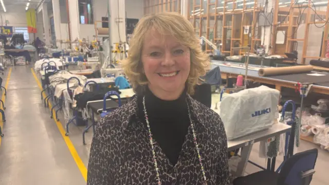 A woman stands by a row of sewing machines
