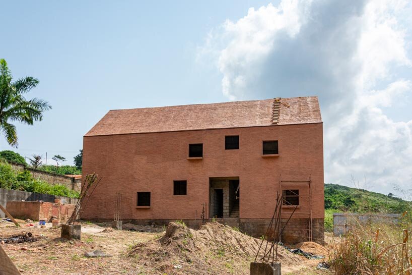 clay monolithic villas emerge from ghana’s red earth landscape