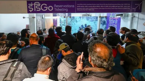 Hindustan Times via Getty Images Passengers seen in heavy rush and chaos at the IndiGo counter at Indira Gandhi International Airport Terminal 1 after a technical glitch at IndiGo caused delays and cancellations of multiple flights on December 4, 2025 in New Delhi, India