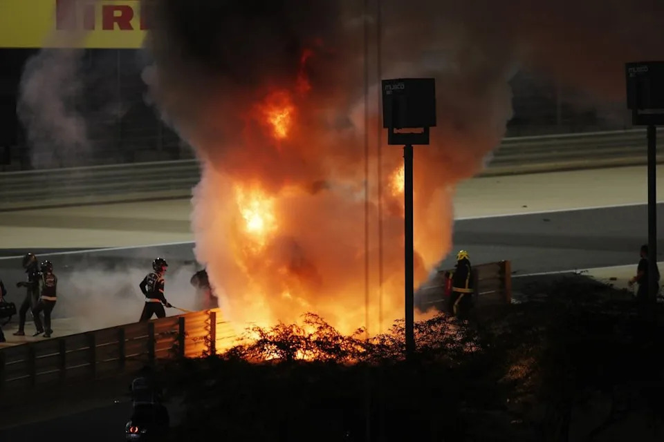 Fire marshals attend an inferno after Romain Grosjean, Haas VF-20, crashed heavily on the opening lap of the Bahrain Grand Prix. The race was stopped. Romain Grosjean, Haas F1, is escorted away on the left of the picture