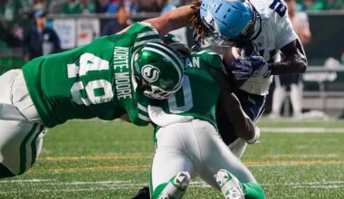 Toronto Argonauts' Deonta McMahon (right) is tackled by Saskatchewan Roughriders' Lake Korte-Moore (49) and Rolan Milligan Jr. (0) during the second half of CFL football action in Regina, on Thursday, July 4, 2024.