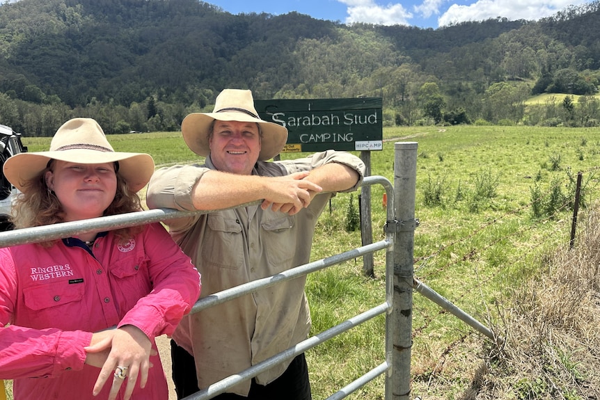 woman and man leaning on fence at farm