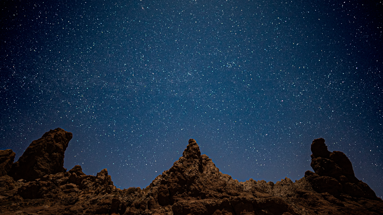 interesting rock formations with jagged peaks and a starry sky above.