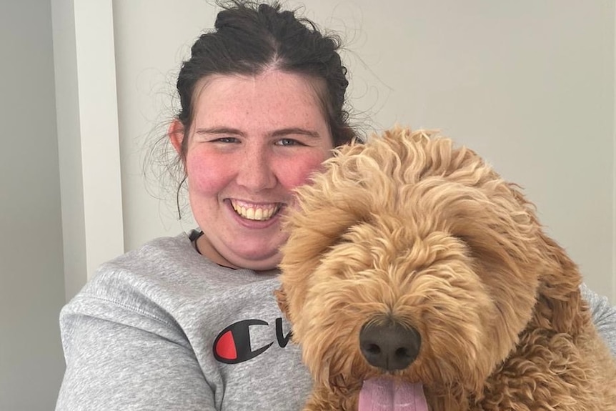 Young woman holds dog while smiling