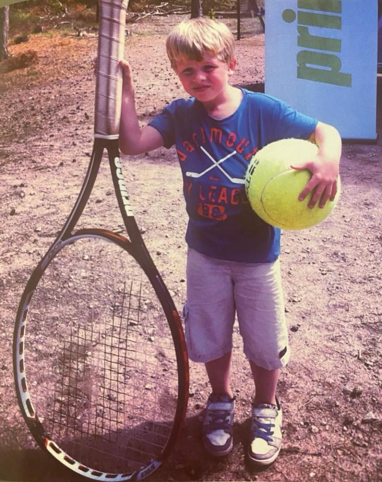 A young Max Dahlin poses with an oversized tennis racket and ball.