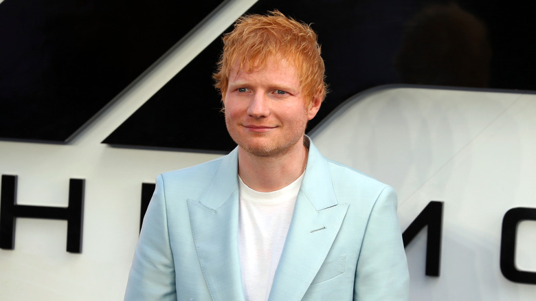 Ed Sheeran in a light blue suit smiling at an event
