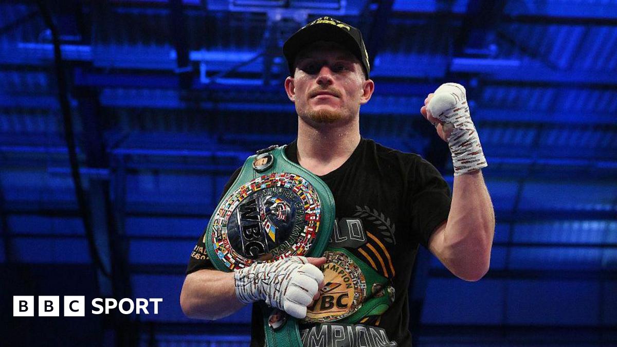 Dalton Smith poses in a dark baseball cap after a win, with a raised left fist and a title belt over his right shoulder