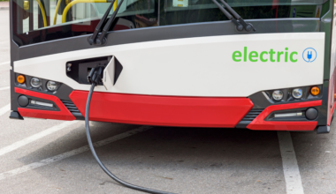 The front of an electric bus, plugged in to charge.