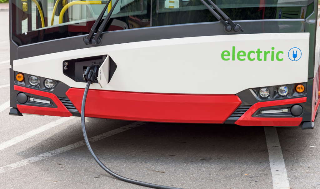 The front of an electric bus, plugged in to charge.