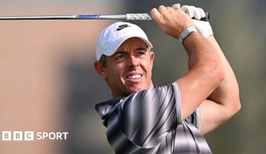 Rory McIlroy watches his shot as he holds a club above his head