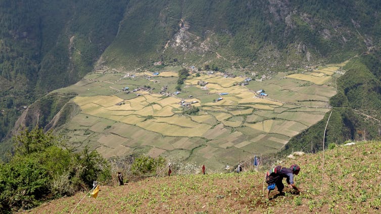 A woman in the foreground bendds over infront of a valley