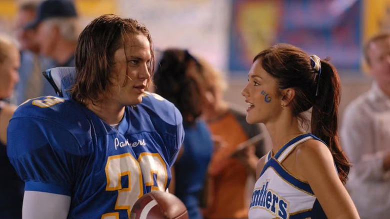 Tim Riggins stands on the sidelines in his football gear talking to Lyla Garrity on Friday Night Lights