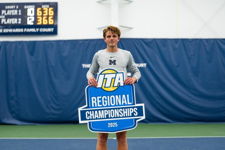 Max Dahlin poses with an ITA Regional Championships sign on the tennis court.