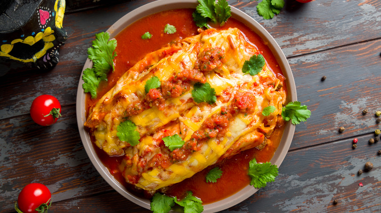 Top view of enchilada with beef and tomato sauce on wooden table