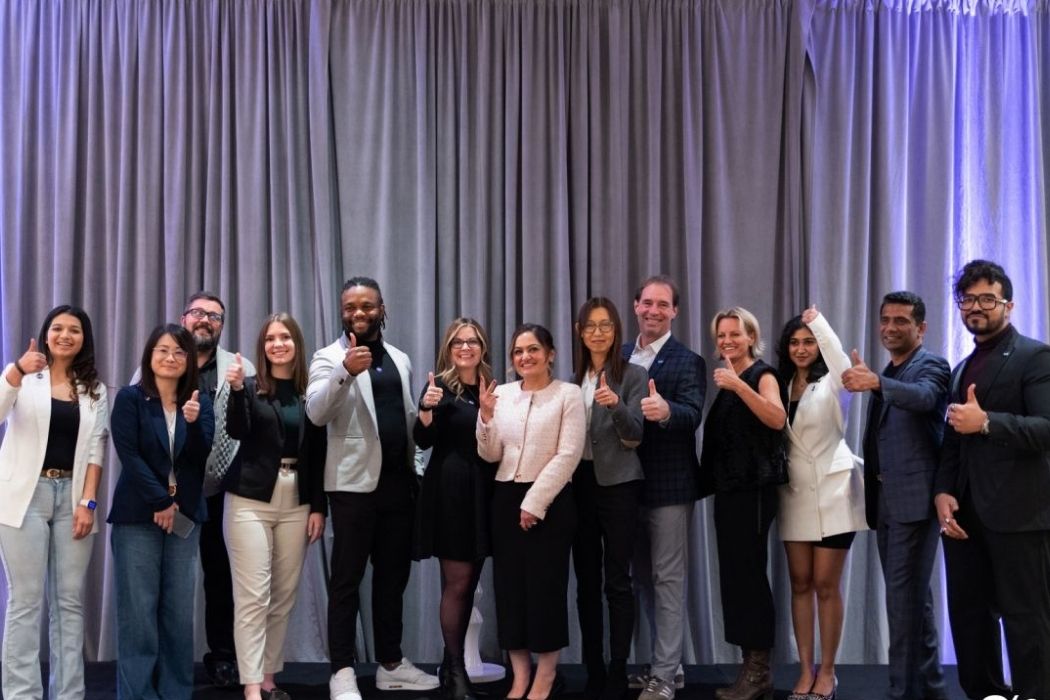 A group of well-dressed people standing in a line, smiling.