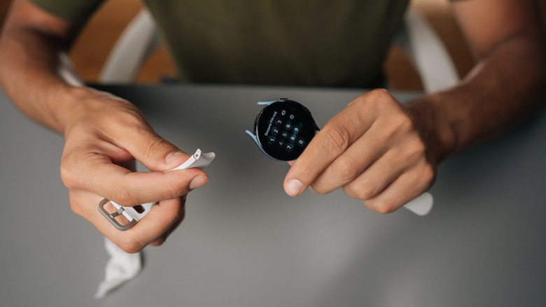 A smartwatch is held in hand with its strap taken off.