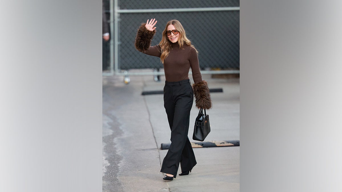 Kristen Bell wearing a brown top with fur cuffs outside 
