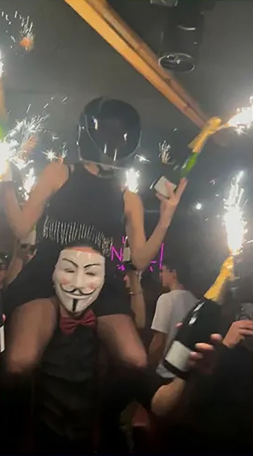 An image shared on social media shows what appears to be a waiter holding champagne bottles with sparklers attached to them. A portion of this image was blurred by CNN to protect identities.