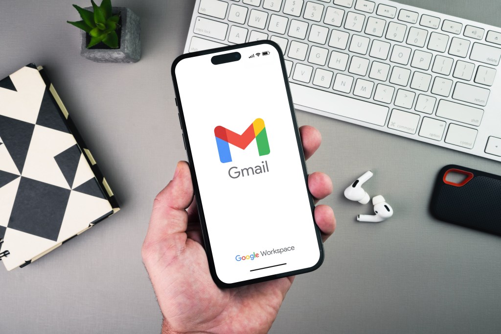 Man holding a Smartphone with Gmail logo displayed.