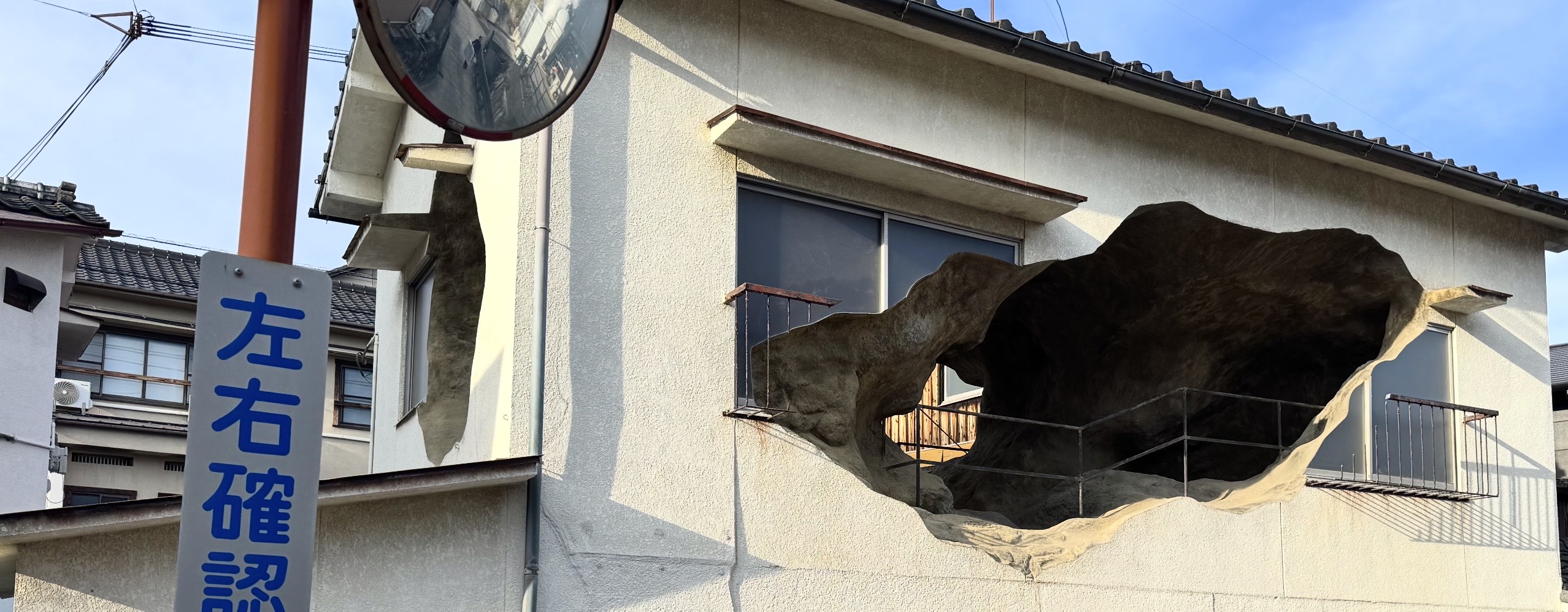 A detail of an art installation comprising a small house with holes in it that open to what looks like a cave on the inside