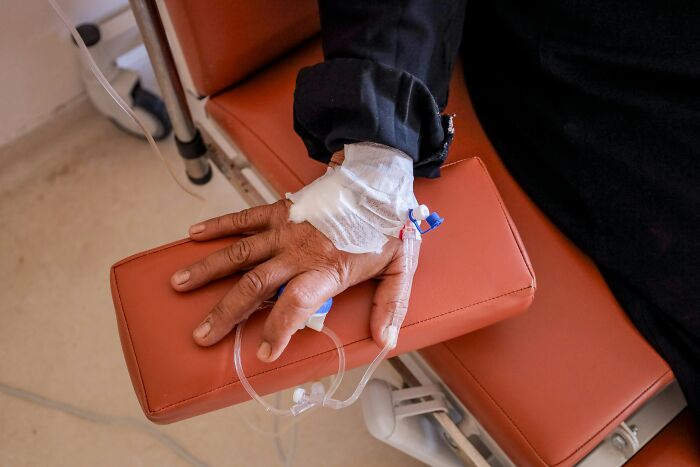 Patient hand with IV line resting on hospital chair arm, representing patients leaving hospital against medical advice.