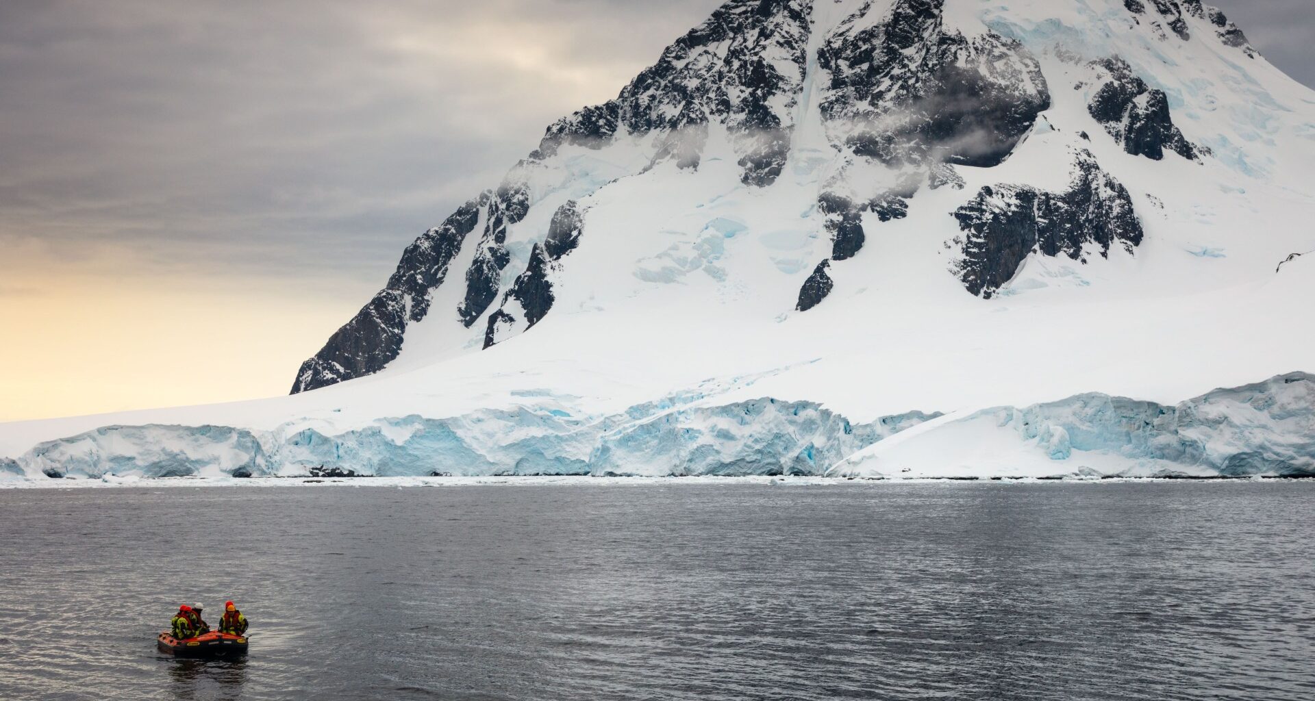 A small boat in the sea, with a snow-covered mountain visible in the background