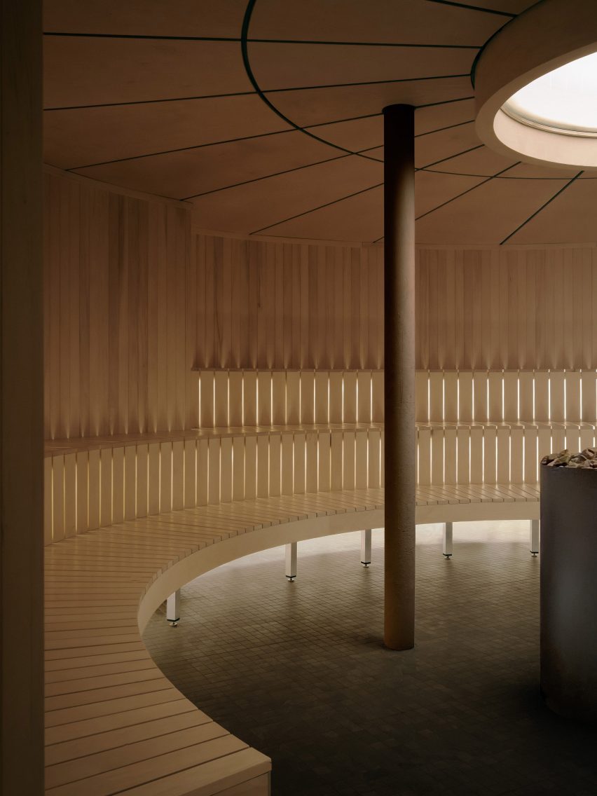 A circular sauna including tiered seating built from wooden slats around its circumference