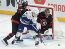 Vancouver Canucks centre Aatu Raty tries to tip the puck past Ottawa Senators goaltender Leevi Merilainen  as he is pressured by defenceman Jordan Spence during game in Ottawa,  Jan. 13, 2026. 