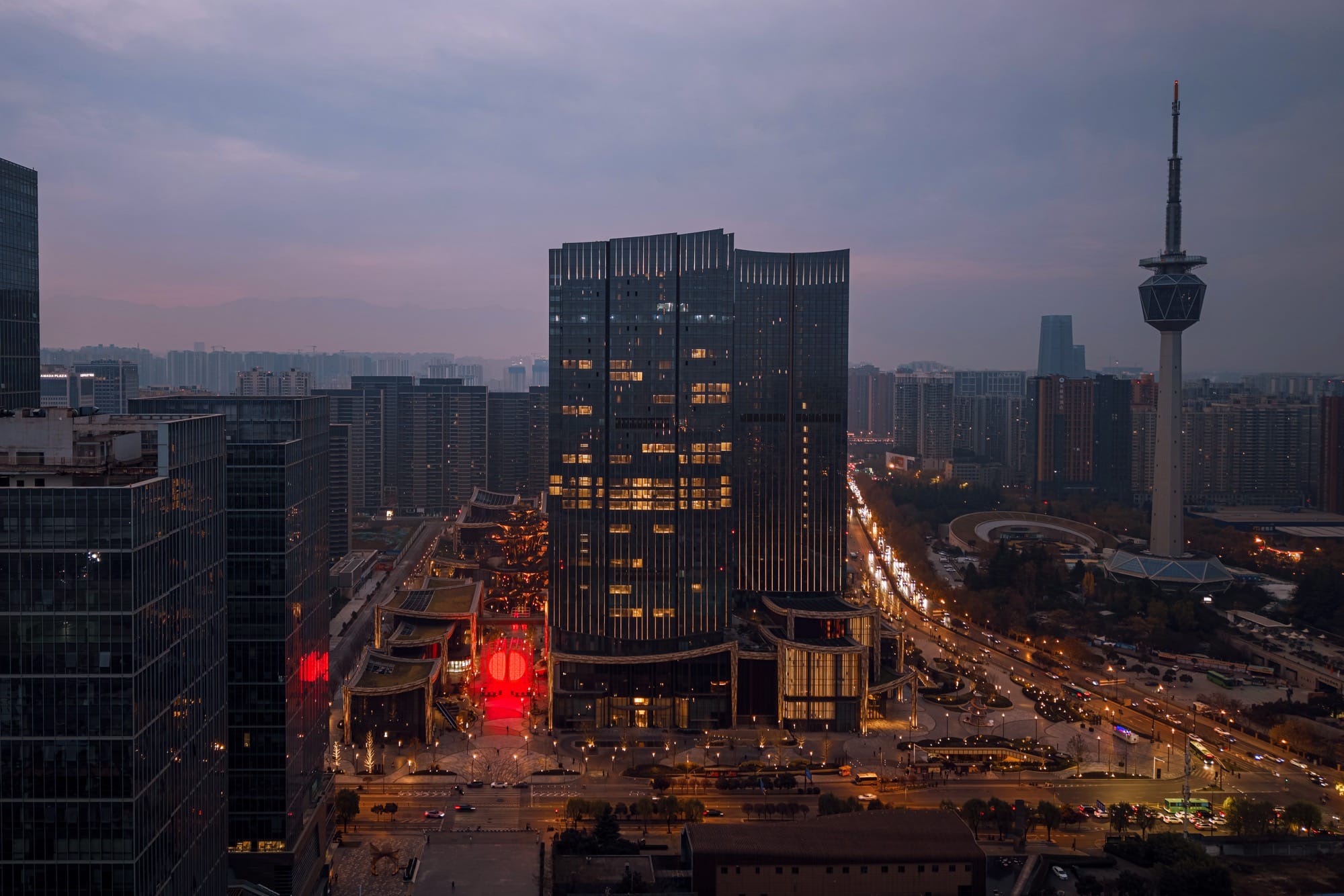 A large-scale installation by SpY of two glowing, red half-spheres within a metal framework, viewed from afar amid the city buildings in Xi'an, China