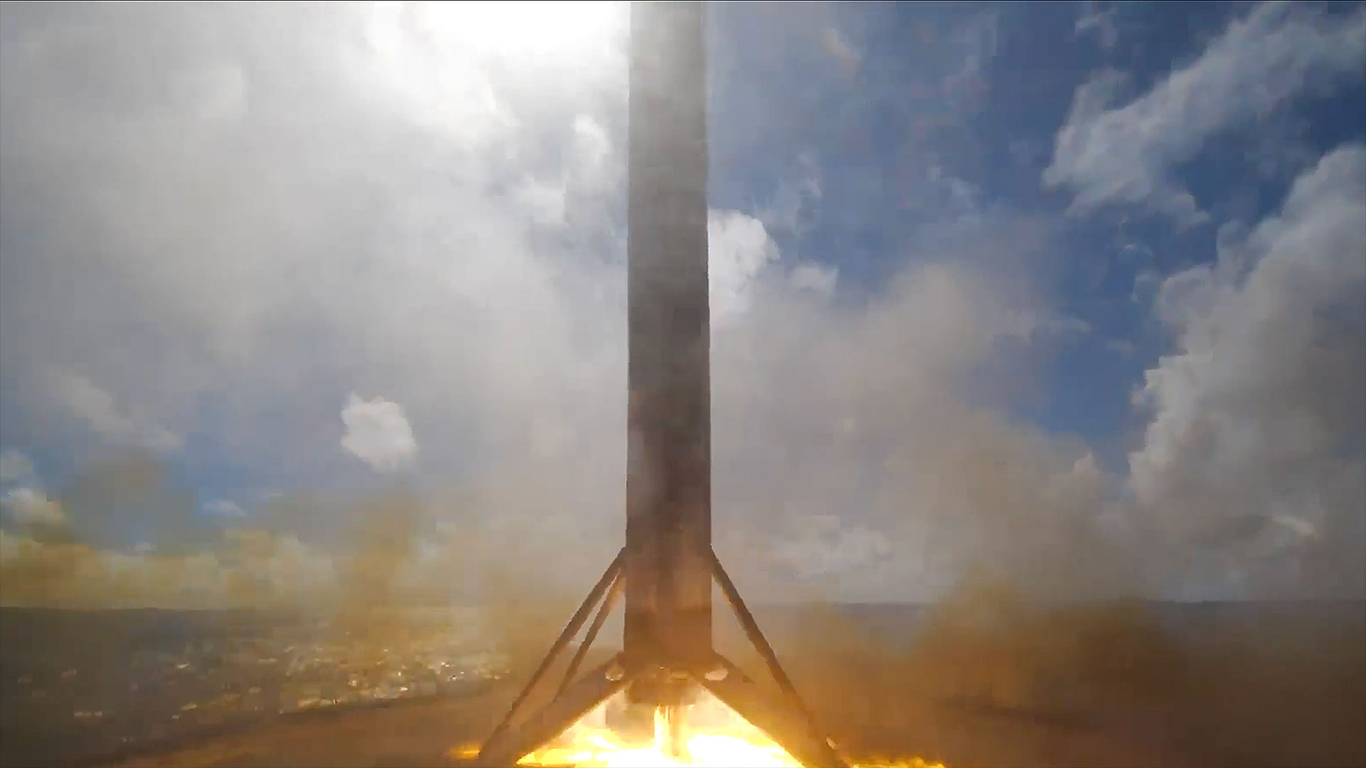 the first stage of an orbital rocket touches down on its four landing legs and the flames of its engine on a sea-based droneship