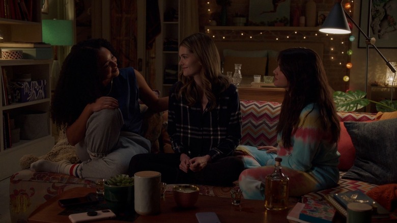 Aisha Dee as Kat sitting on couch looking at Meghann Fahy as Sutton next to Katie Stevens as Jane in The Bold Type