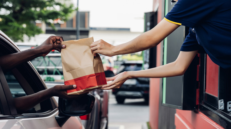 Customer taking food from employee at drive thru