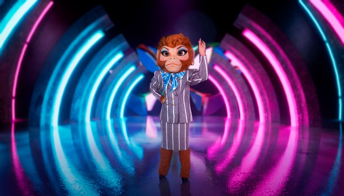 ©ITV Plc Someone dressed as a monkey in a suit jacket and skirt with stripes.