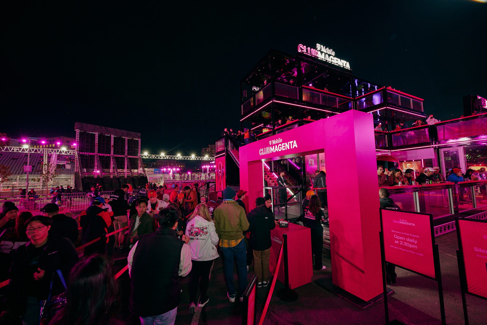 crowd outside a venue at night with a vibrant magenta color scheme