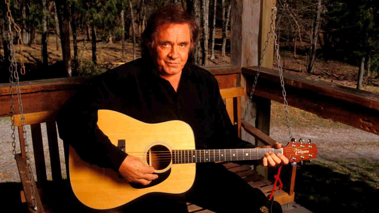 Johnny Cash posing for a photograph with an acoustic guitar