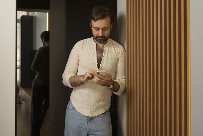 Man using smartphone, leaning against wall, illustrating patients leaving the hospital against medical advice concept.