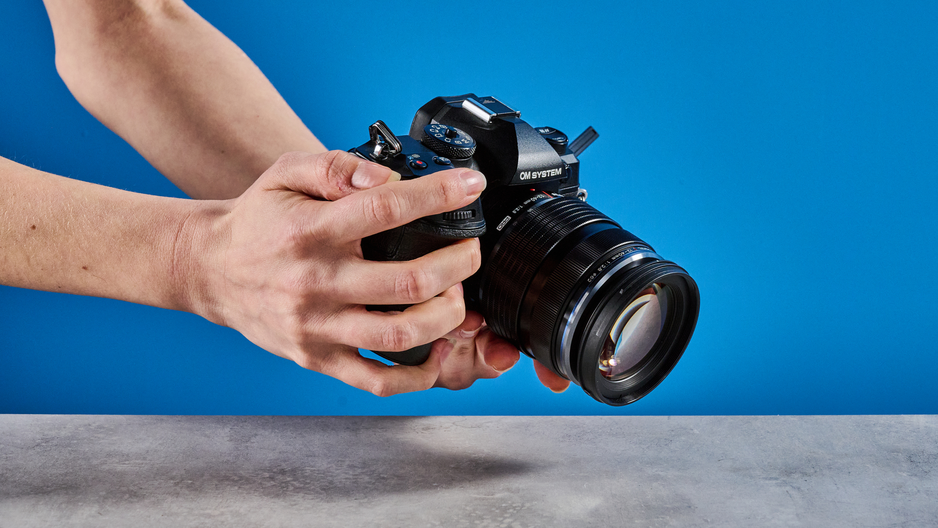 A person holding an OM System OM-1 Mark II in their hands