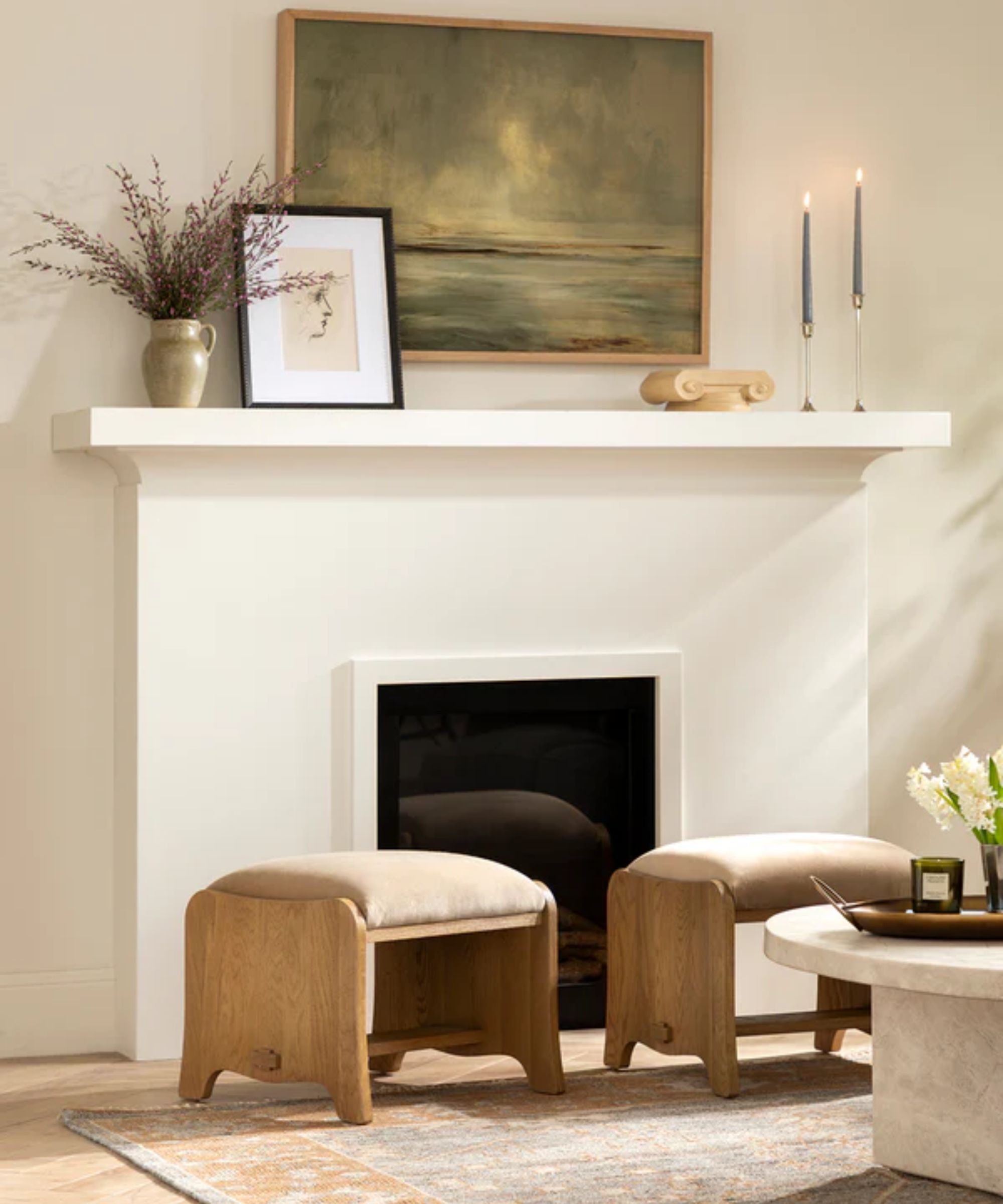 a minimalist fireplace scene with two ottomans in front of the fireplace and decor on the mantel