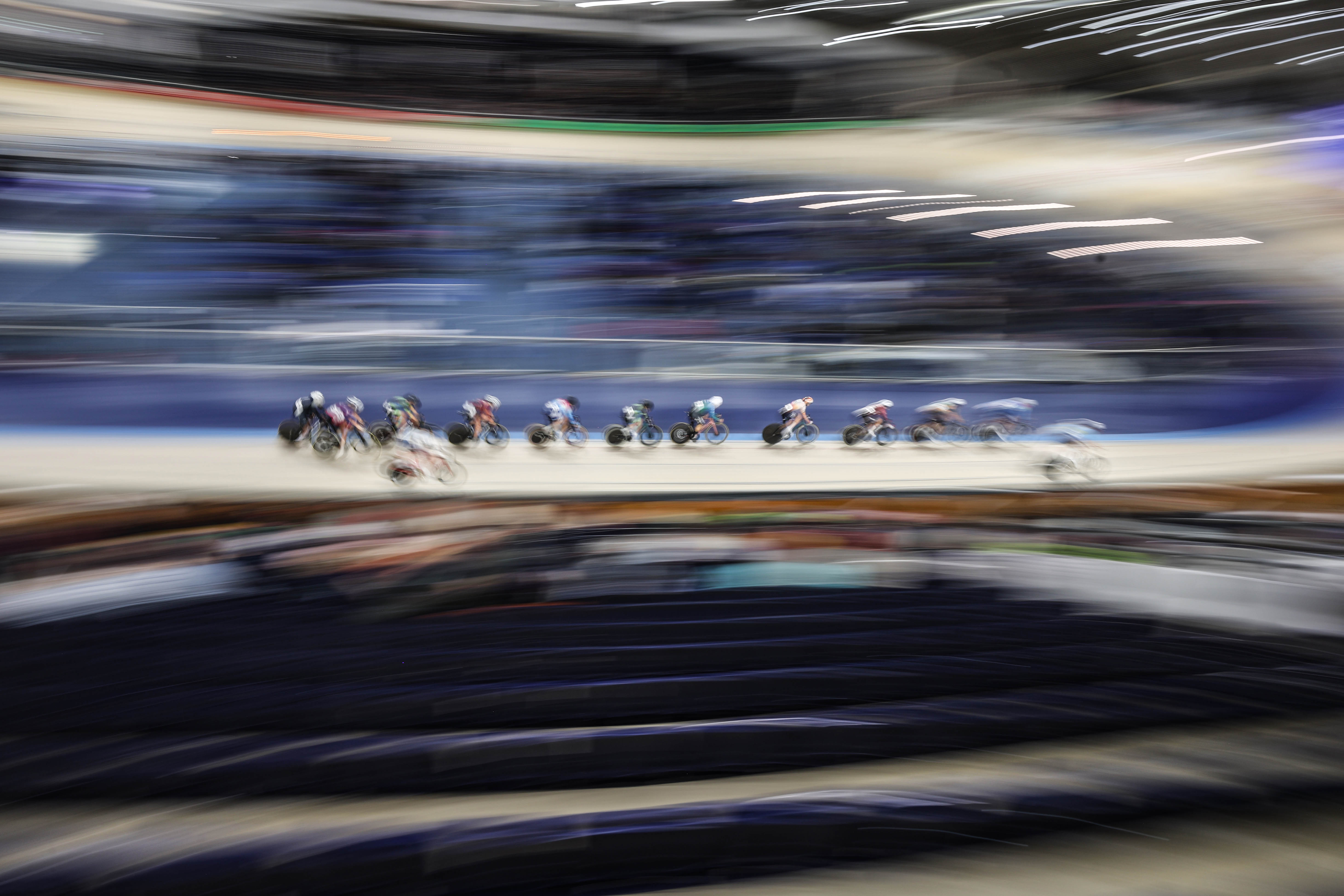 Track cyclists racing at high speed, creating motion blur.
