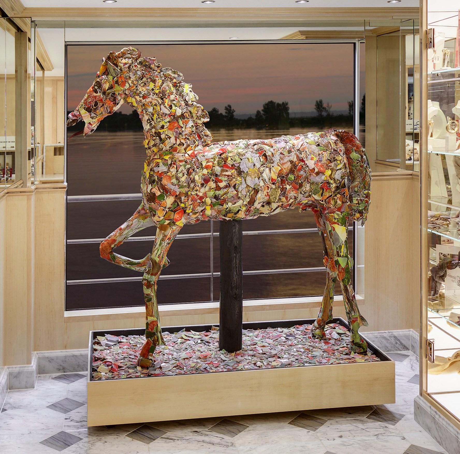 Life-sized glass horse by Pino Signoretto displayed in a lobby.