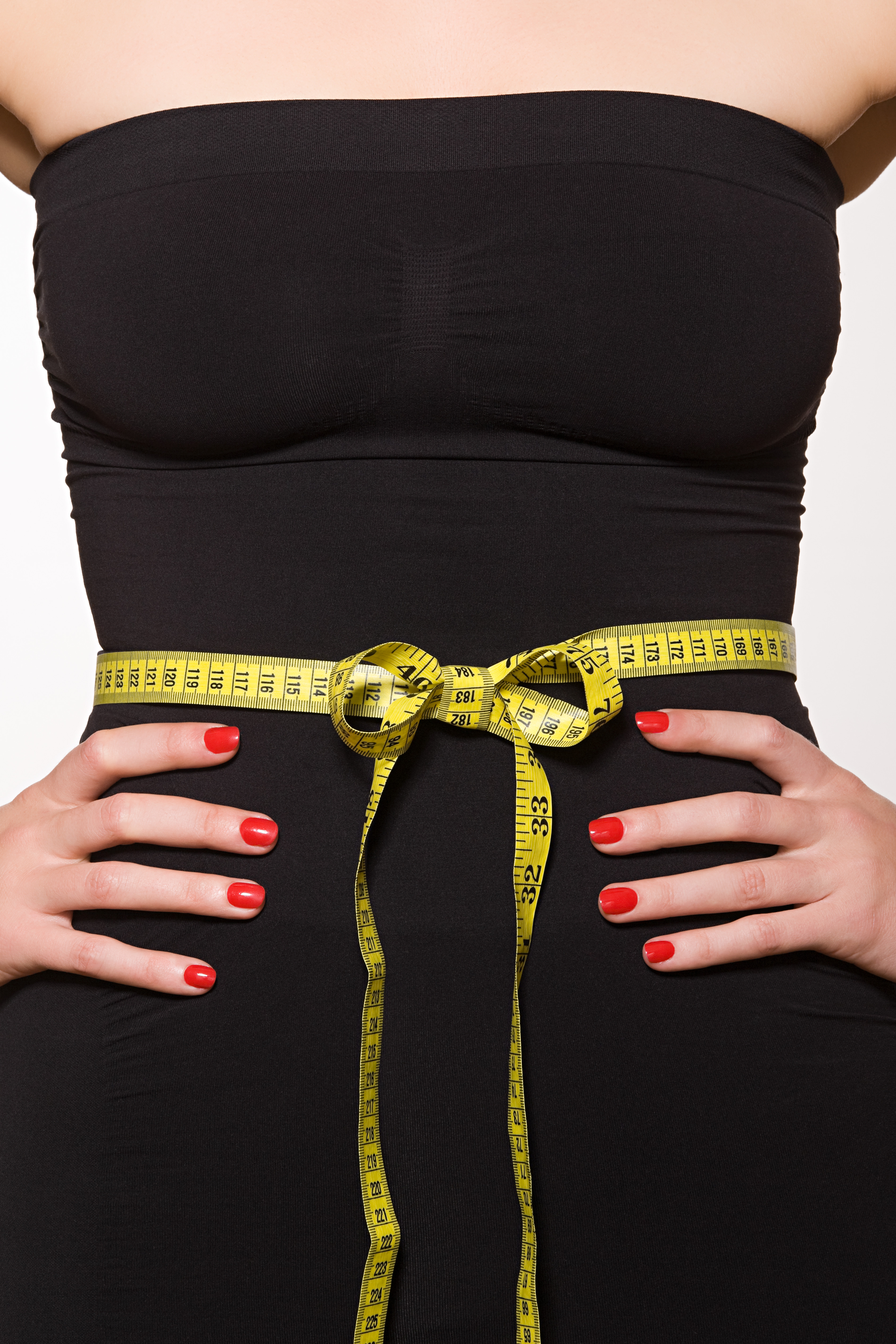 A woman's torso, clad in a black strapless top, with a yellow tape measure tied in a bow around her waist.
