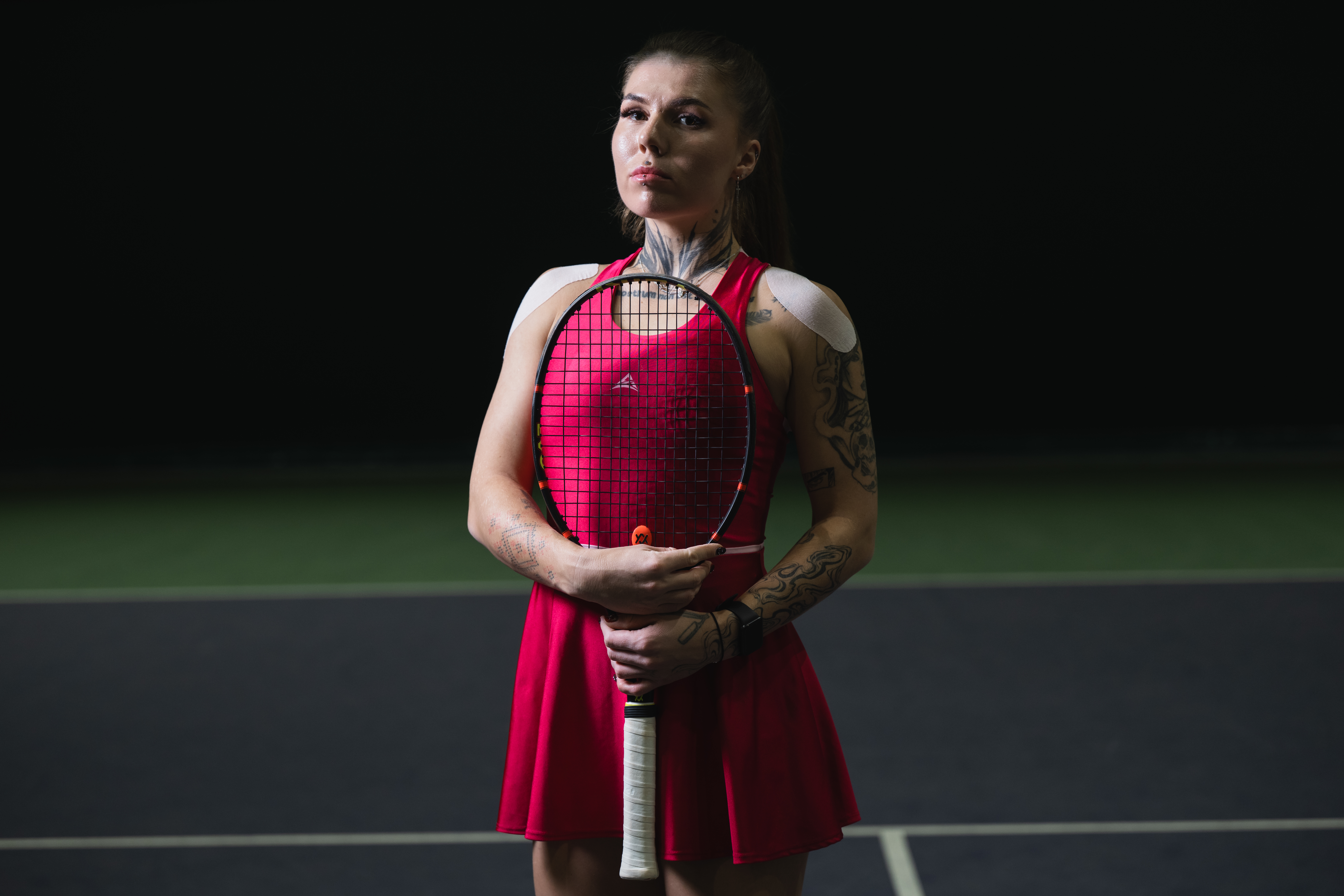 Oleksandra Oliynykova posing with a tennis racket on a tennis court.
