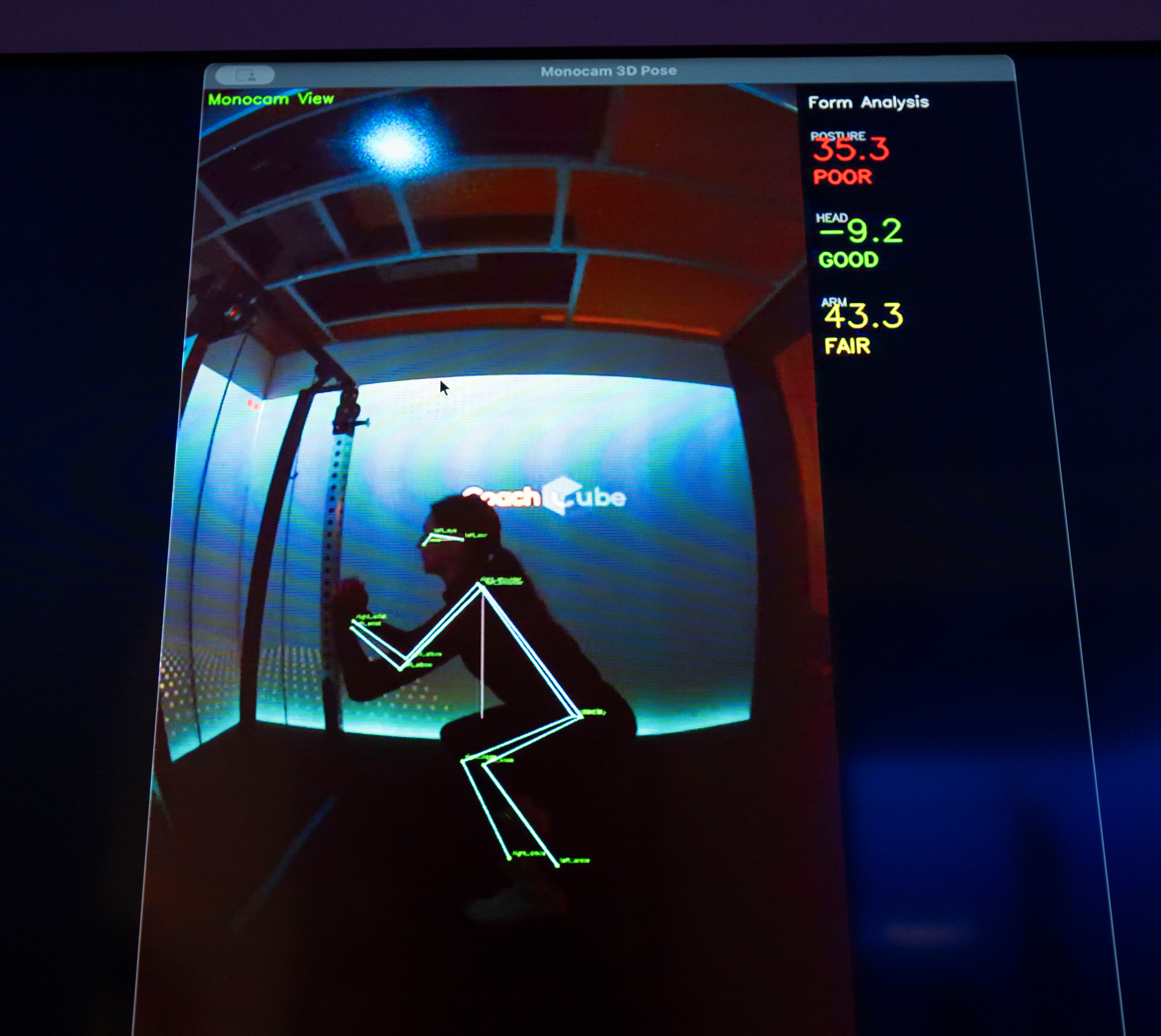 A screen displaying a skeleton-like outline of a person inside a training cube, with form analysis scores on the right.