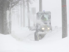 Stephen Minielly clears snow from a driveway along Watford's Main Street Saturday afternoon