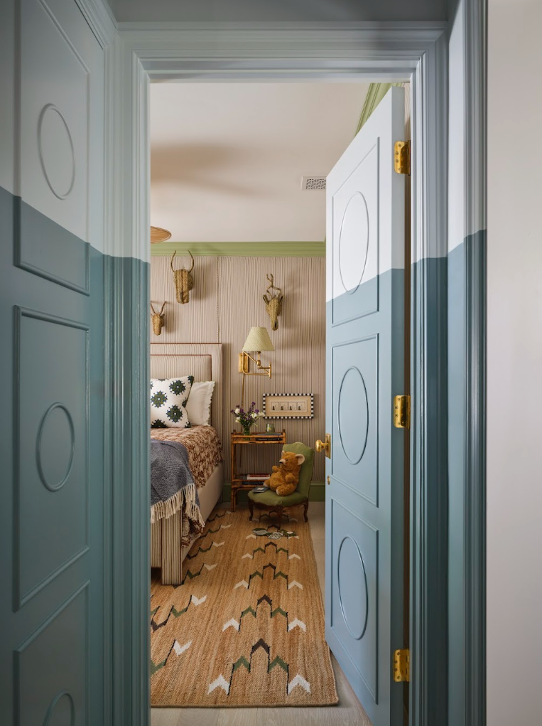 View into a softly decorated bedroom through double doors.