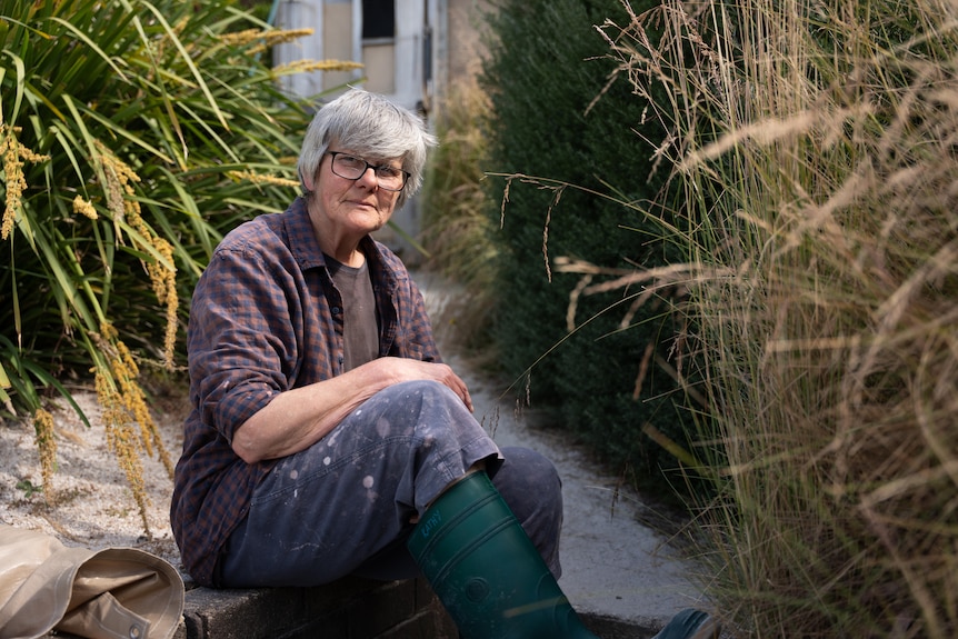Kathy Grievson, a woman in working clothes, sits on the beach.