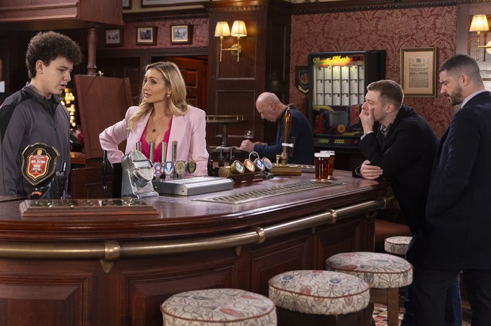Daniel looks deep in thought beside Adam as Eva stands behind the bar staring at Will in the Rovers in Coronation Street