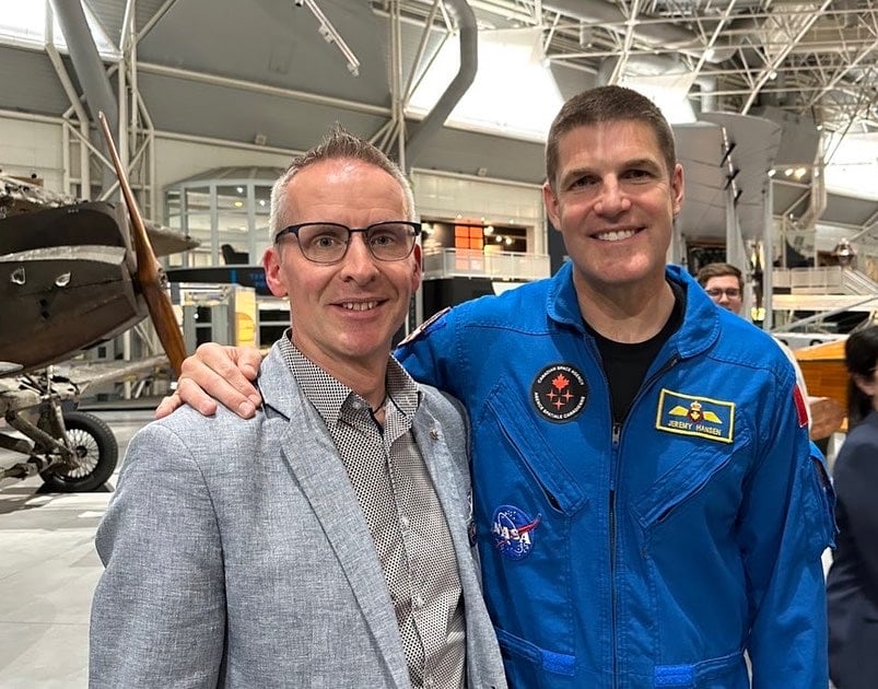 Two men posing, one in a NASA flight suit.