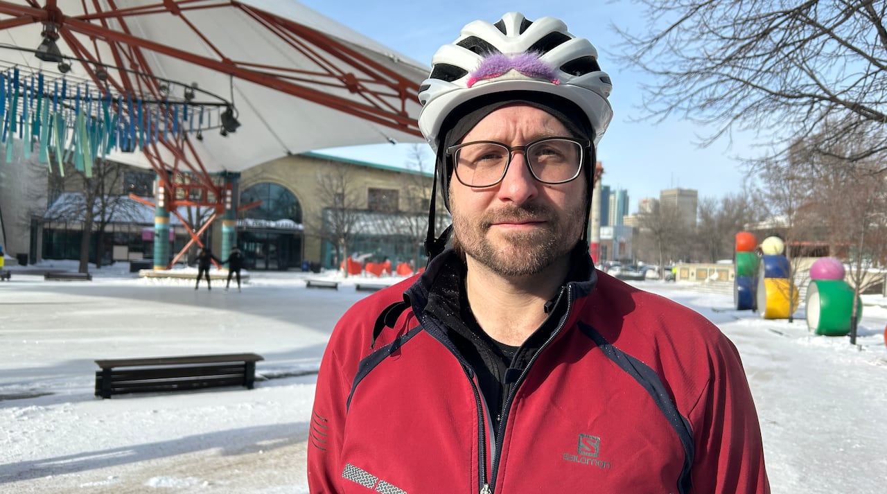 Man with beard wears a red jacket and a white bike helmet on a winter day